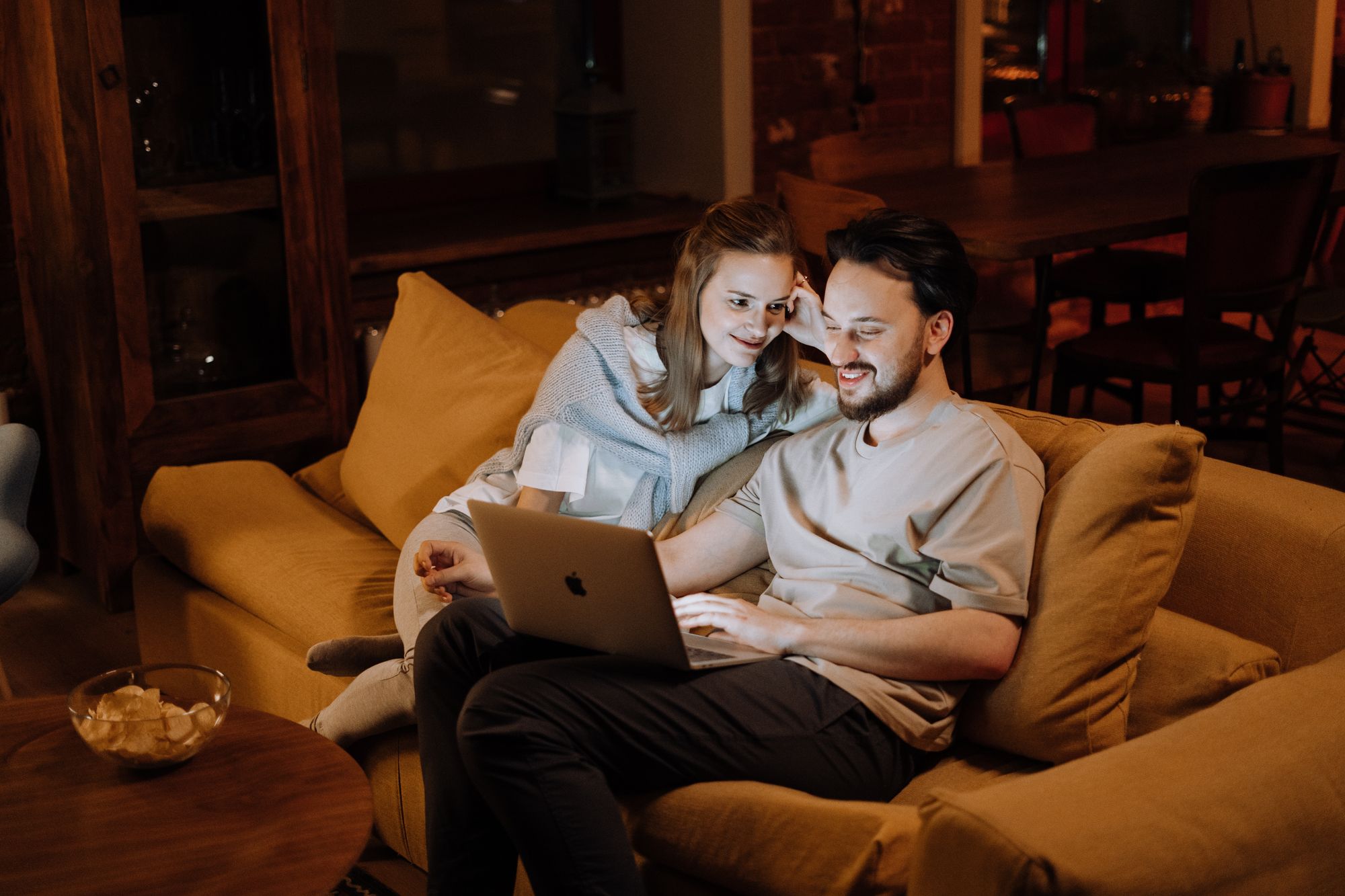 A smiling couple looking at a laptop together at home